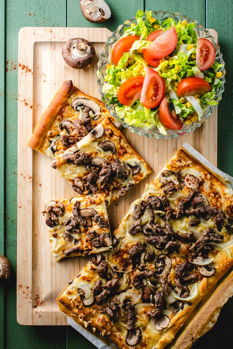 Pizza med storfestrimler, aromasopp, løk og frisk salat