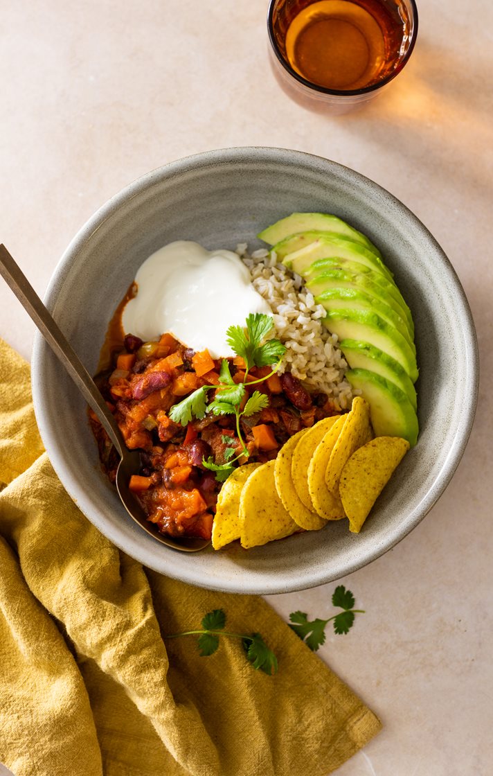 Chili sin carne med sorte bønner, servert med rømme, avokadoskiver og nachochips