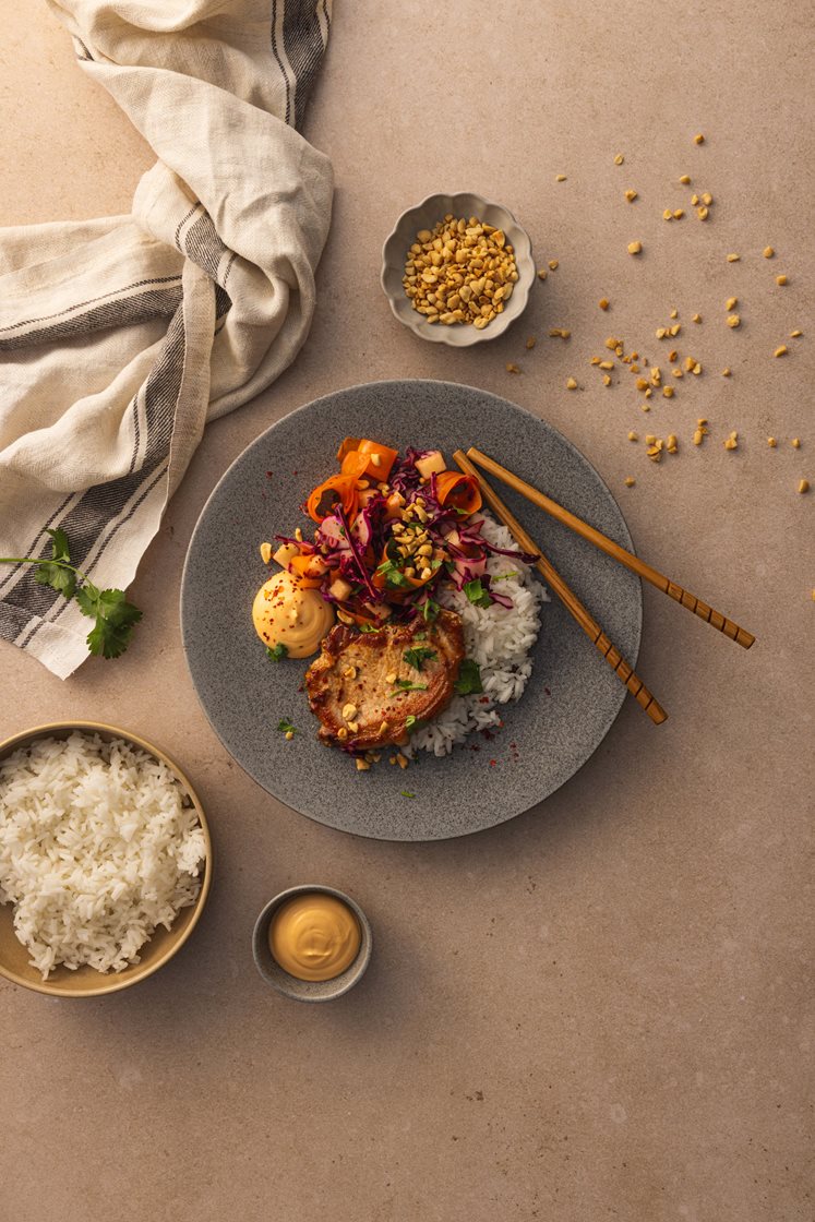 Asiatisk svinekam med rødkålsalat og ris, servert med peanøtter, koriander og chilimajones