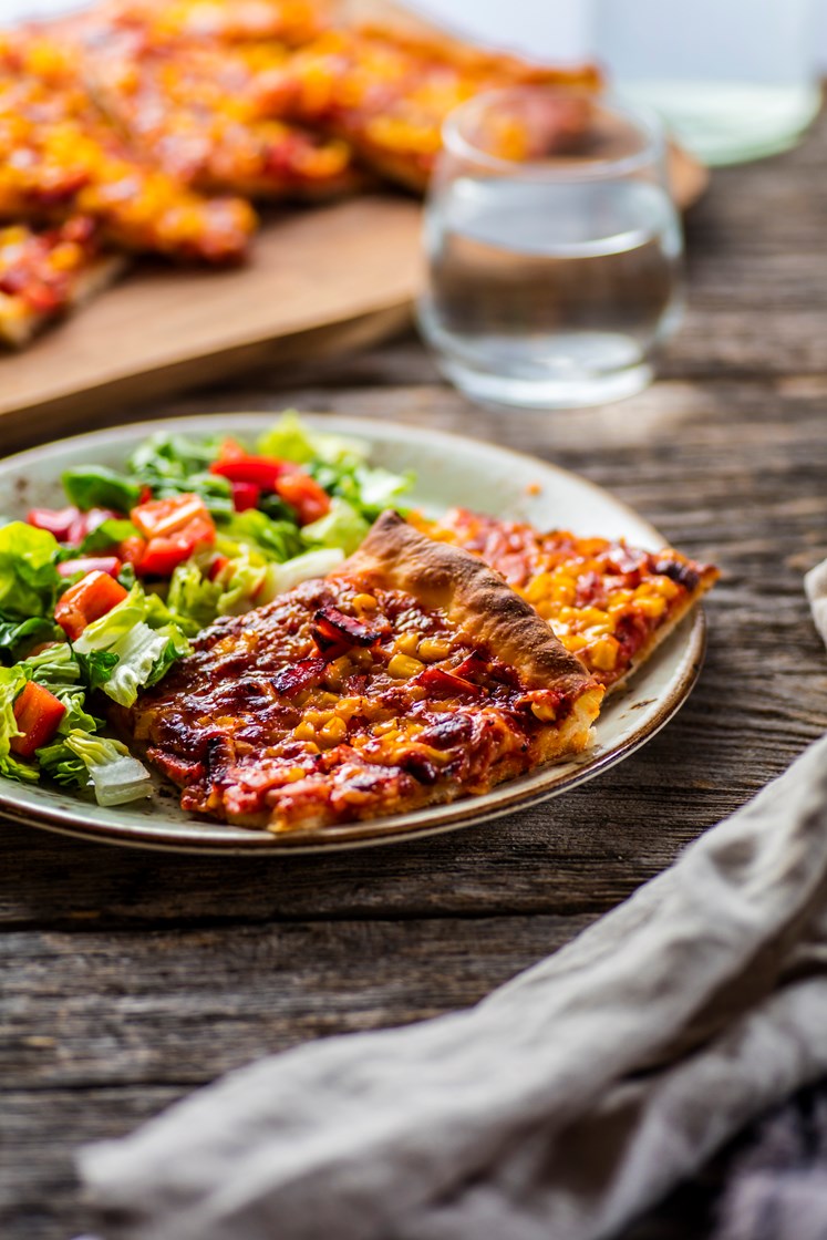 Pizza med mozzarella, skinke og mais, servert med frisk salat