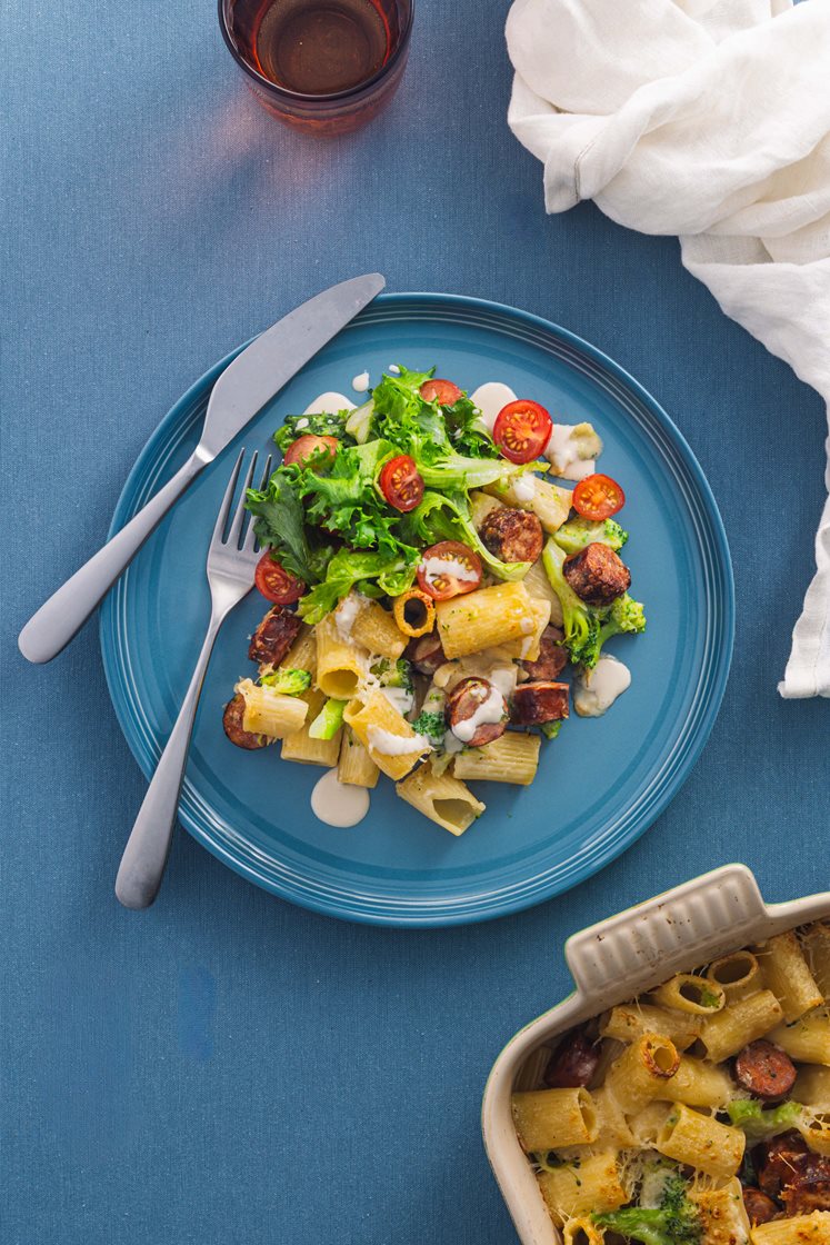 Pastagrateng med trøffelpølser og brokkoli servert med grønn salat med cherrytomater