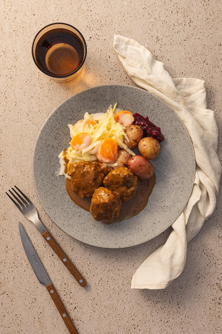 Kjøttkaker i brun saus med stuede gulrøtter og kål, servert med kokte poteter og rørte tyttebær