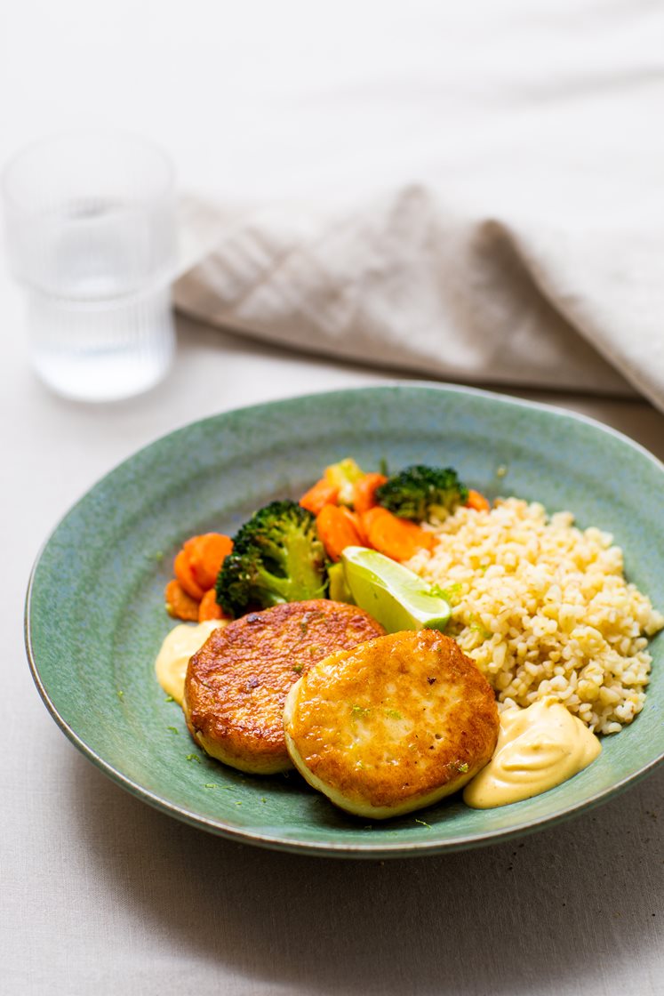 Fiskekaker med bulgur og ingefærstekte grønnsaker, servert med curry- og mangodressing