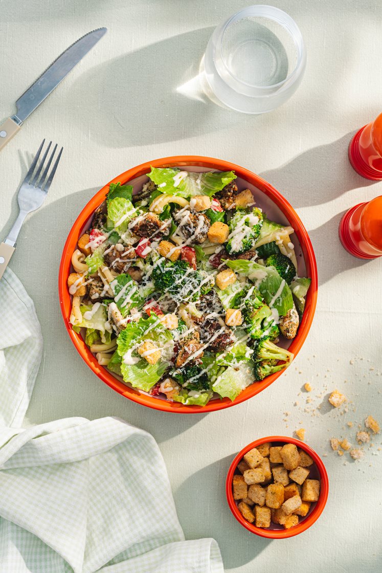 Pastasalat med kylling, brokkoli og cæsardressing, toppet med urtekrutonger