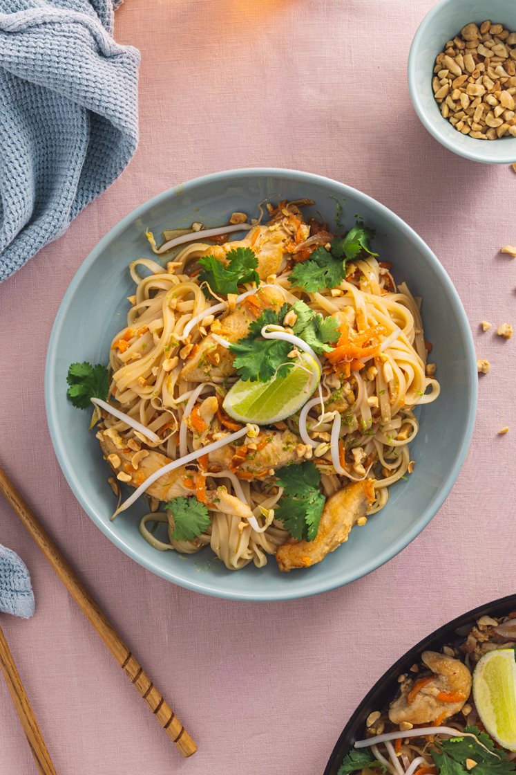 Pad thai med kyllingfilet, eggenudler og bønnespirer, toppet med hakkede peanøtter og koriander