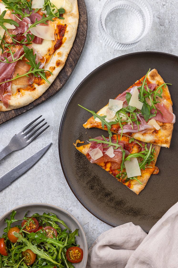 Pizza Parma toppet med ruccola og Grana Padano, servert med tomatsalat