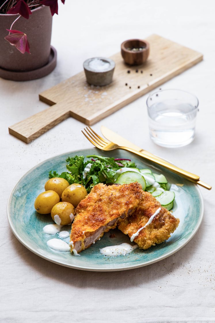 Svineschnitzel med kokte småpoteter, servert med syrlig agurksalat