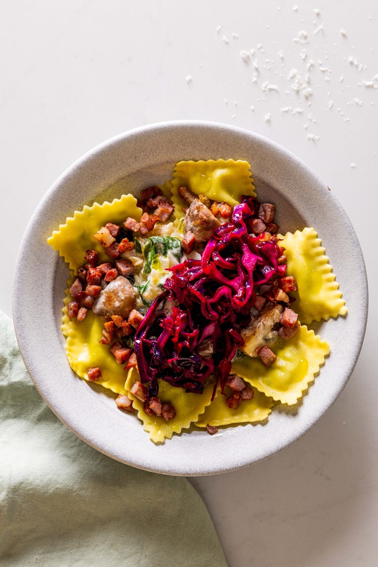 Ravioli med ricotta servert med sjampinjong i kremet spinatsaus, toppet med bacon og syrlig rødkål