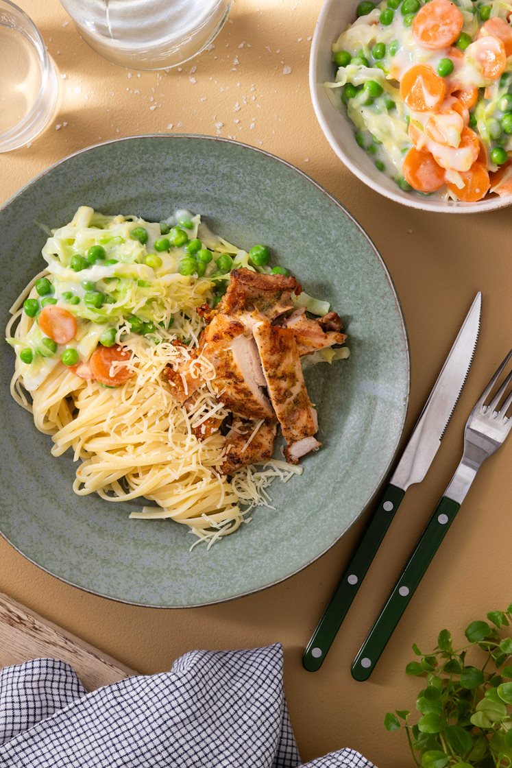 Pasta med stekt kylling, grønne erter og spisskål i hvit saus