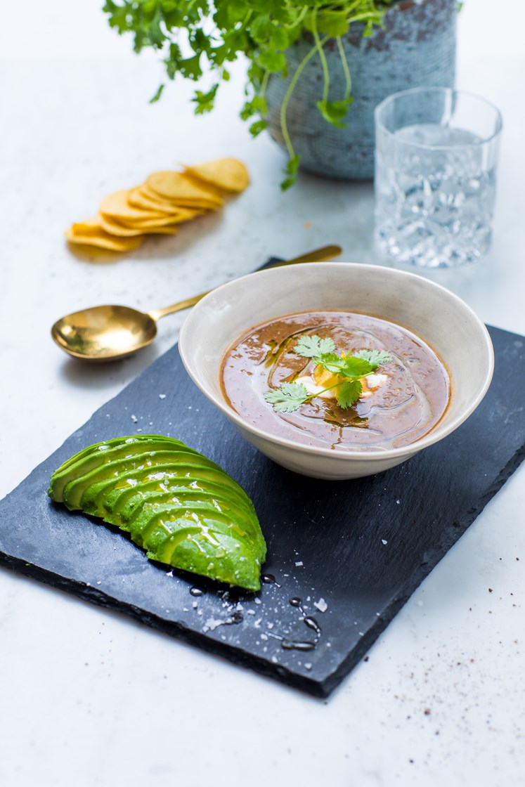Fyldig tomatisert bønne- og linsesuppe servert med ris, avokado og nachochips