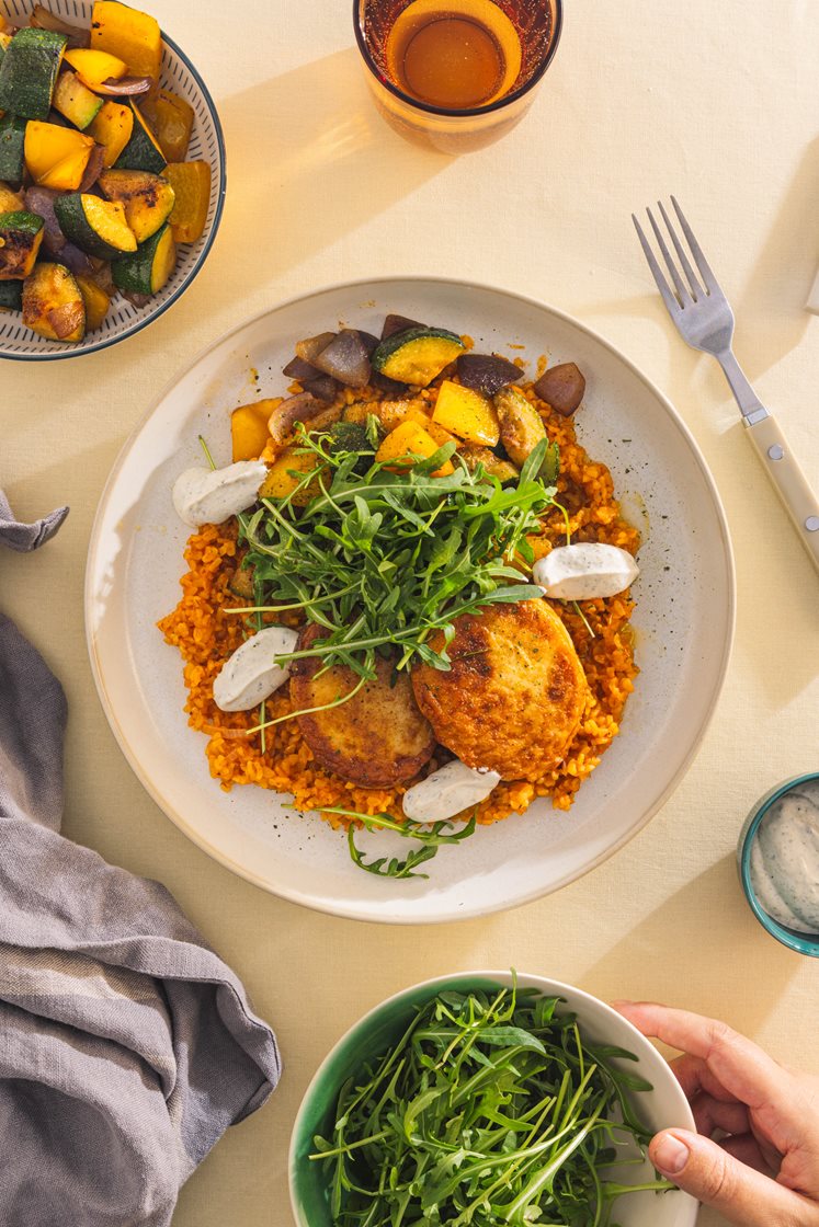 Fiskekaker med tomatbulgur, stekte grønnsaker, ruccola og persillade-rømme