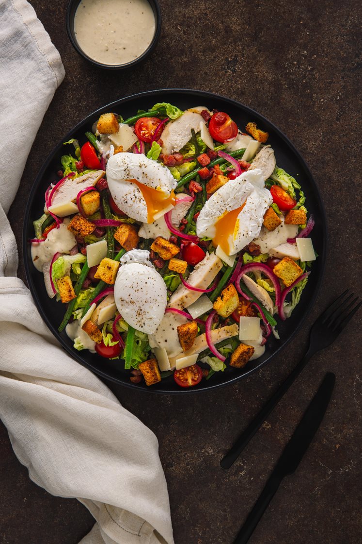 Cæsarsalat med kylling og bacon, servert med brioche-krutonger, aspargesbønner og posjert egg 