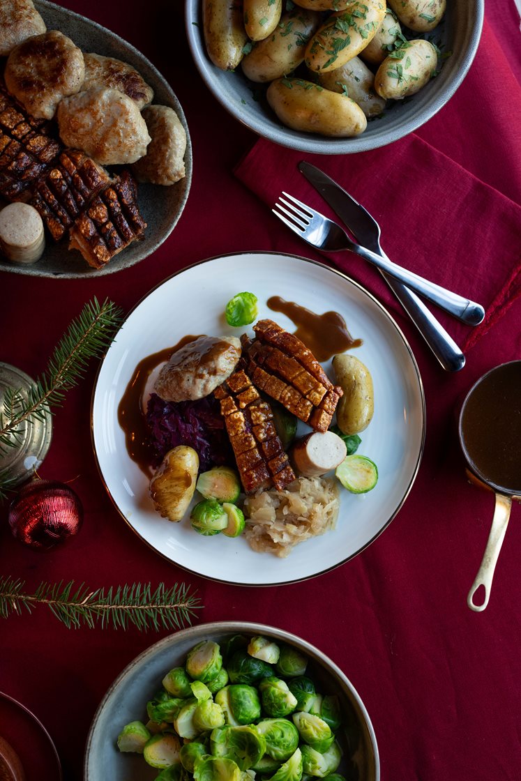 Juleribbe med mandelpoteter, rødkål, rosenkål og medisterkaker, servert med brun saus og rørte tyttebær