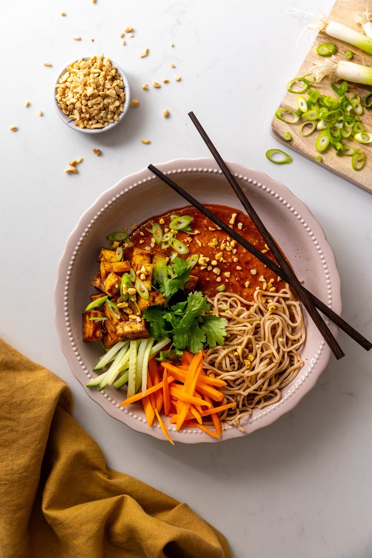 Hoisinstekt tofu og fullkornsnudler i spicy chili- og peanøttsaus, toppet med vårløk og koriander