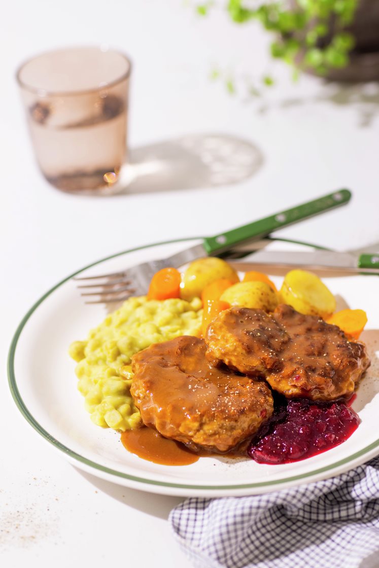 Grove karbonader i brun saus med kokte poteter, gulrøtter, ertestuing og rørte tyttebær