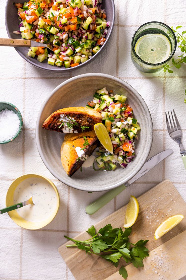 Pitabrød fylt med krydret storfe- og lammekjøttdeig, servert med tomatsalat og urtedressing