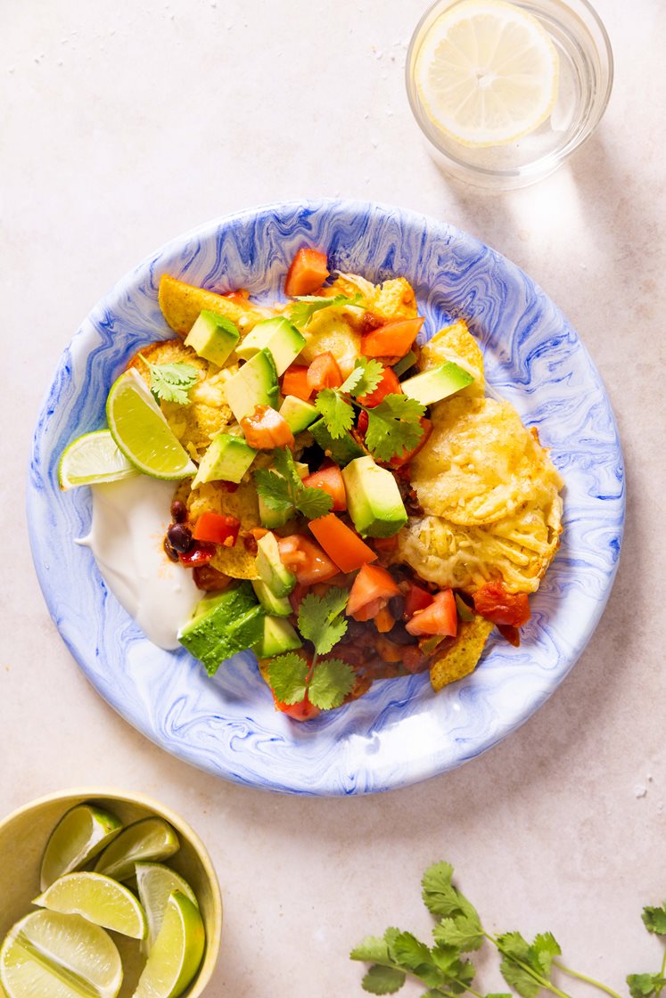 Gratinerte nachos med bønner, avokado og tomat, toppet med koriander og rømme