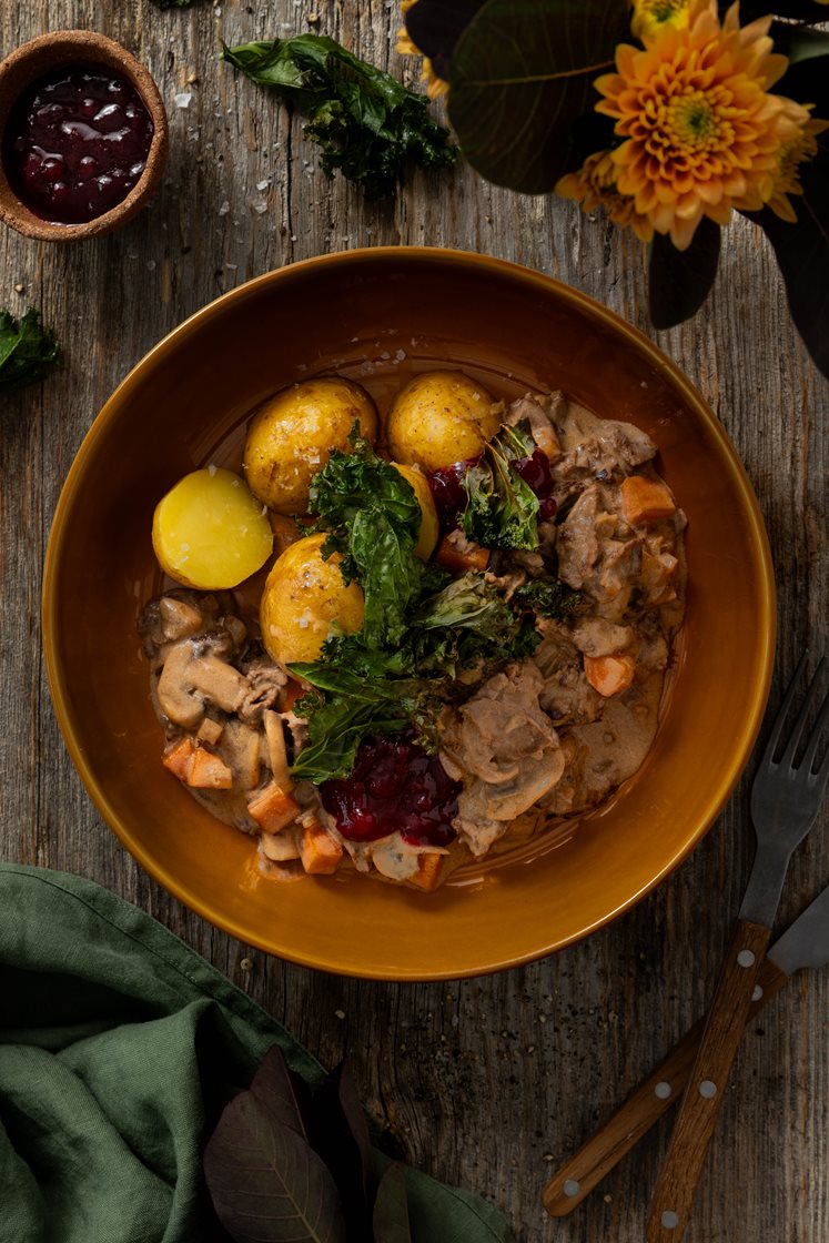 Krondyrragout med smag af Karl Johan-svampe, serveret med rørte tyttebær og sprød grønkål