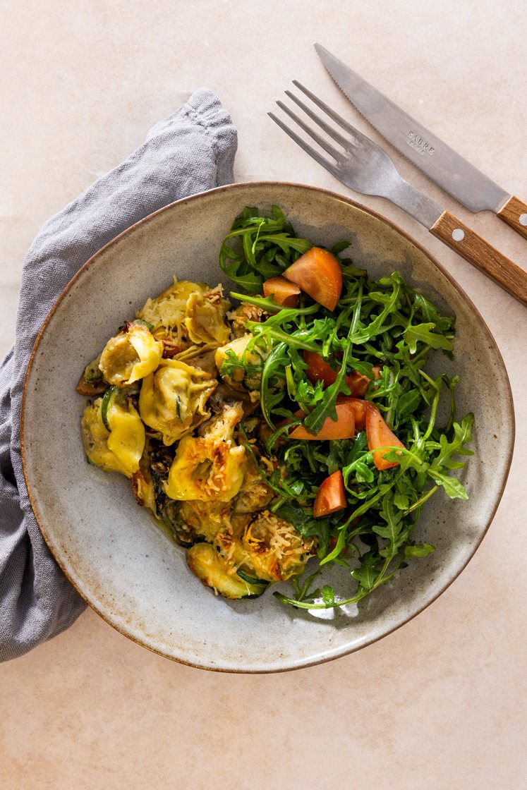 Gratinert steinsopptortelloni med squash og spinat, servert med ruccola- og tomatsalat