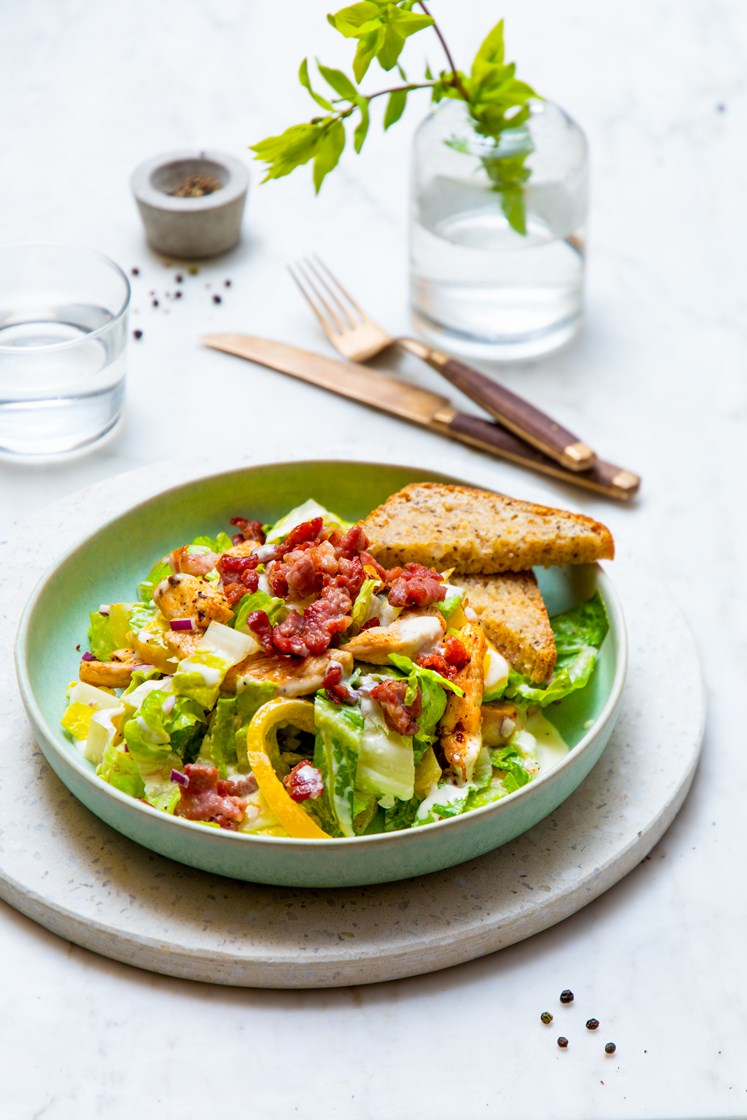 Cæsarsalat med kylling og bacon servert med steinovnsbakte brød