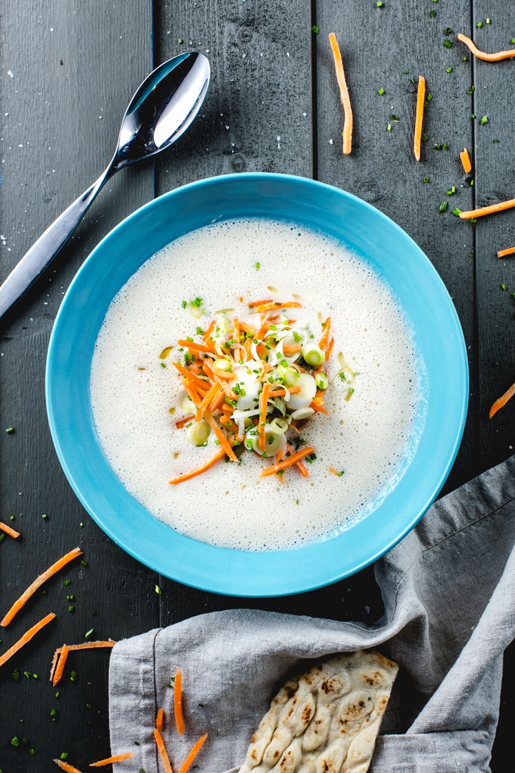 Fiskesuppe med reker, revet gulrot og minipurreløk servert med langbrød