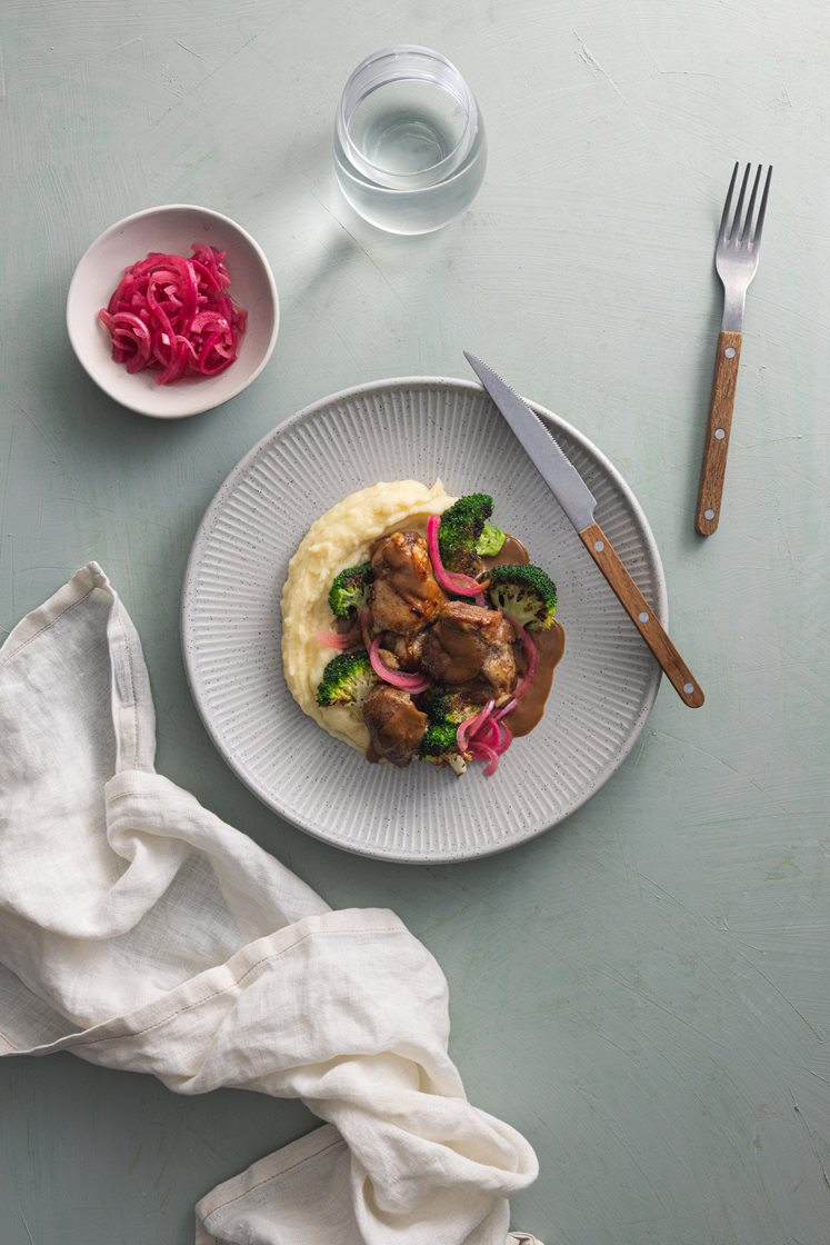 Mørkokt svinebog med syltet rødløk og brokkoli, servert med potetmos og peppersaus