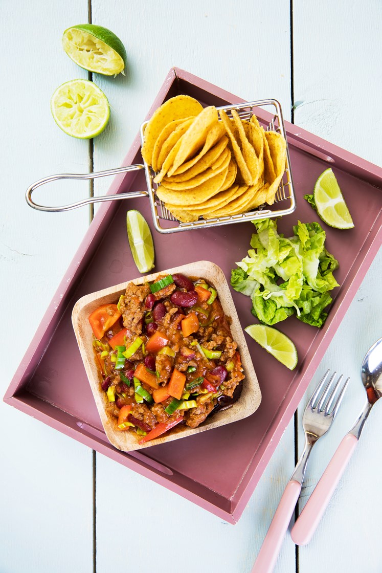 Chili con carne med bønner, paprika og purreløk servert med tortillachips, salat og rømme