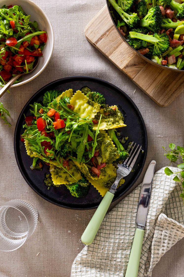 Ravioli i pesto med bacon, broccoli og tomatsalat