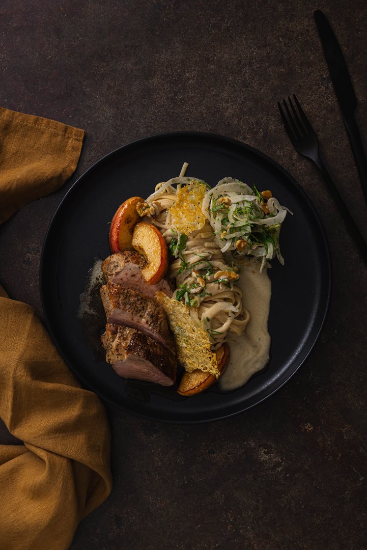 Svinefilet med steinsoppkremet pasta, servert med honningbakt eple, valnøtter og ostechips
