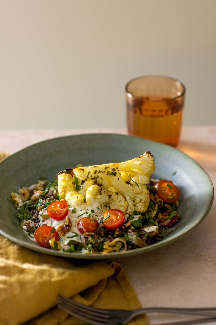 Bakt blomkål i kryddersmør med bulgur- og belugalinsesalat med tomater, servert med urtedressing