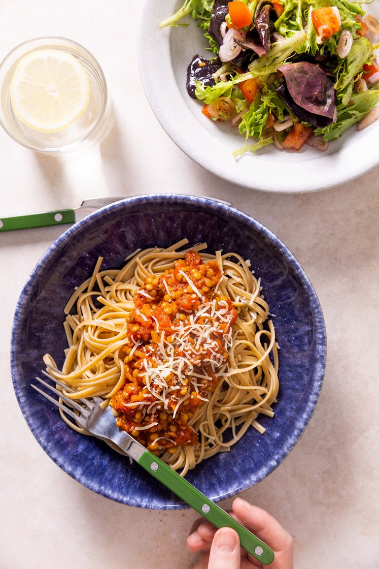 Rask linse-bolognese og pasta, servert medtomatsalat og revet Grande Premium