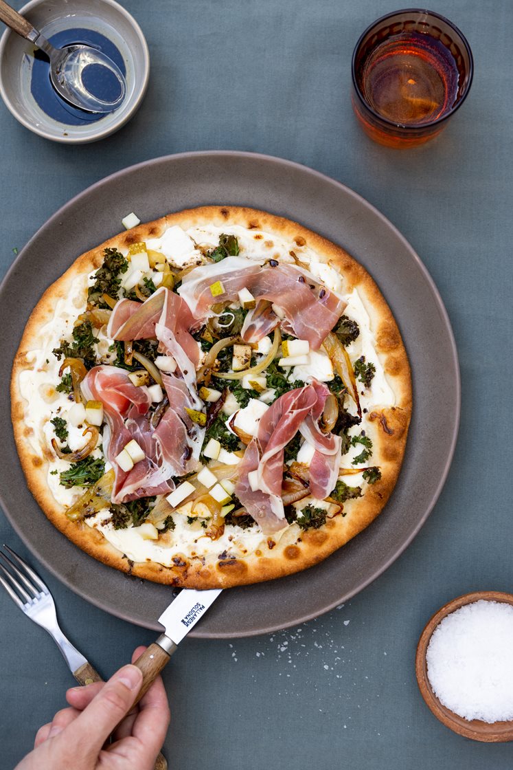 Pizza Bianca med honningsyltet løk, chevre og grønnkål, toppet med parmaskinke og pære