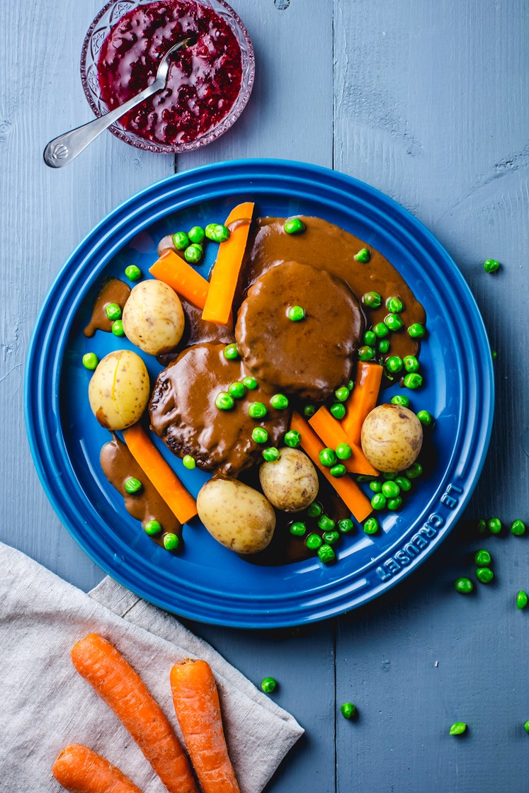 Karbonader i brun saus med gulrøtter, erter, småpoteter og rørte tyttebær
