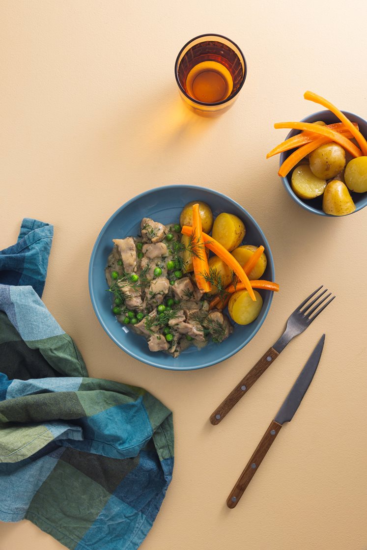 Dillkjøtt av mørkokt svinebog servert med grønne erter, kokte gulrøtter og poteter