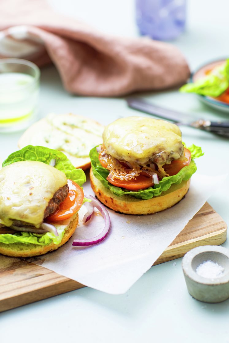 Saftig burger i briochebrød med ost, ramsløkaioli, frisk salat og tomatskiver 