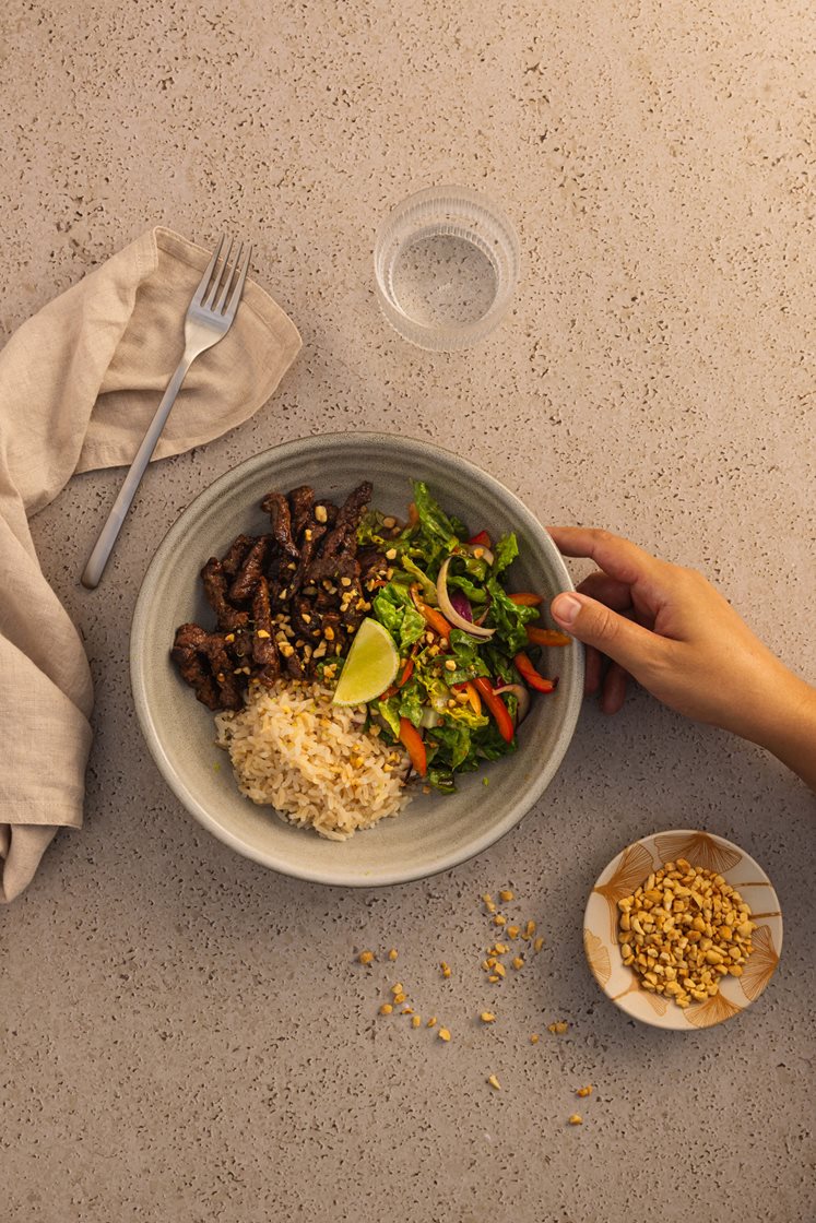 Thaisalat med biffstrimler og friske grønnsaker, servert med peanøtter og fullkornsris