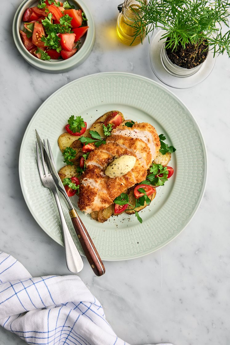 Pankostekt kyckling med pommes Lyonnaise, persiljesmör och tomatsallad