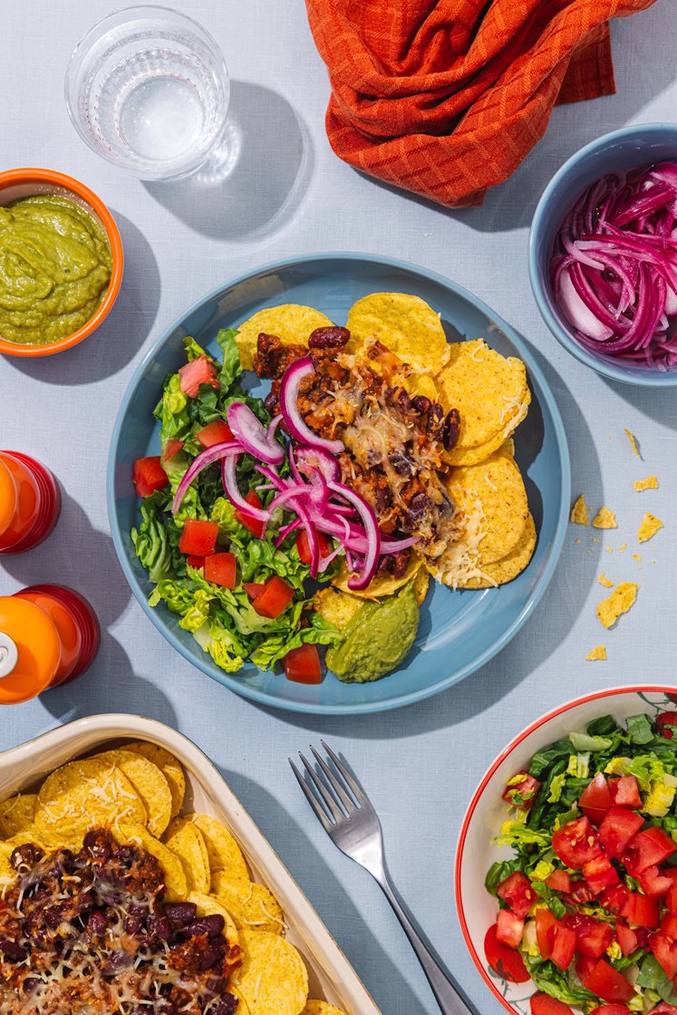 Ostegratinerte nachos med chili con carne, toppet med syltet rødløk, salat og guacamole