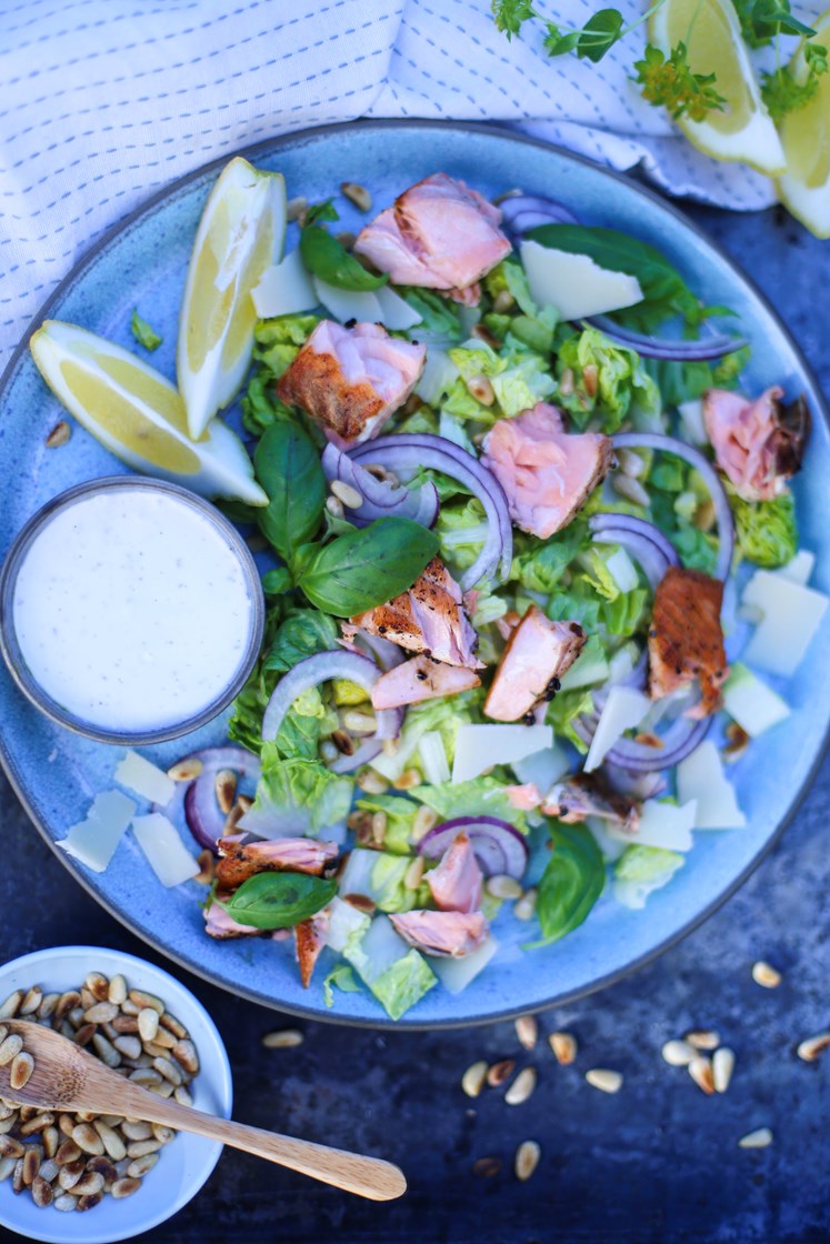Salat med stekt laks, pinjerkjerner, rødløk og grana padano servert med frisk dressing
