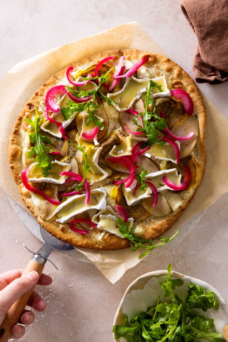 Hvit pizza med norsk brie, pære og honninglasert rødløk, servert med ruccolasalat